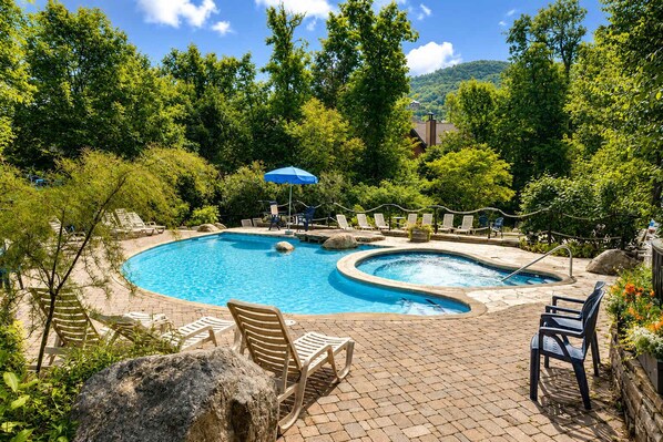 A circular pool with lounge chairs and a hot tub, surrounded by trees and a mountain backdrop. - Tremblant village SKI resort, 10 m walk or shuttle (Mont-Tremblant)