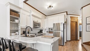 Una cocina con armarios blancos, una isla central, un microondas, una estufa y un refrigerador.