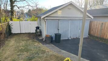 A residential garage with a white exterior, a wooden fence, and a paved driveway.