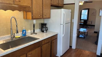 A kitchen with wooden cabinets, a stainless steel sink, a white refrigerator, and a coffee maker.