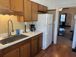 A kitchen with wooden cabinets, a stainless steel sink, a white refrigerator, and a coffee maker.