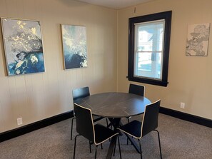 Une salle de conférence avec une table ronde, quatre chaises et trois œuvres d’art encadrées accrochées aux murs.