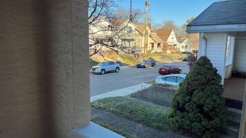 A residential street with houses, parked cars, and a small tree.