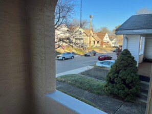 A residential street with houses, parked cars, and a small tree.