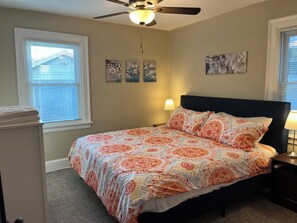 Une chambre à coucher avec un lit, un ventilateur de plafond et des œuvres d’art accrochées aux murs.