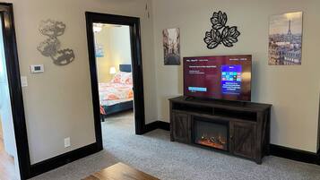 A hotel room with a TV, fireplace, and artwork on the walls.