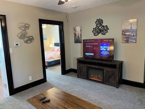 A hotel room with a TV, fireplace, and artwork on the walls.