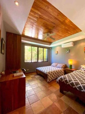 A bedroom with two beds, a desk, and a ceiling fan.