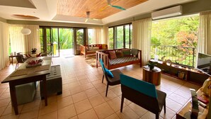 A spacious living area with a wooden ceiling, a dining table, a sofa, and a TV. - Moonshine Inn - 1 BR Studio Loft with Ocean & Jungle Views, Moonshine Inn -- 1BR Studio Loft (Quepos)