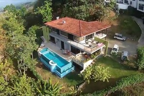 A two-story house with a swimming pool, surrounded by greenery. - Moonshine Inn - 1 BR Studio Loft with Ocean & Jungle Views, Moonshine Inn -- 1BR Studio Loft (Quepos)