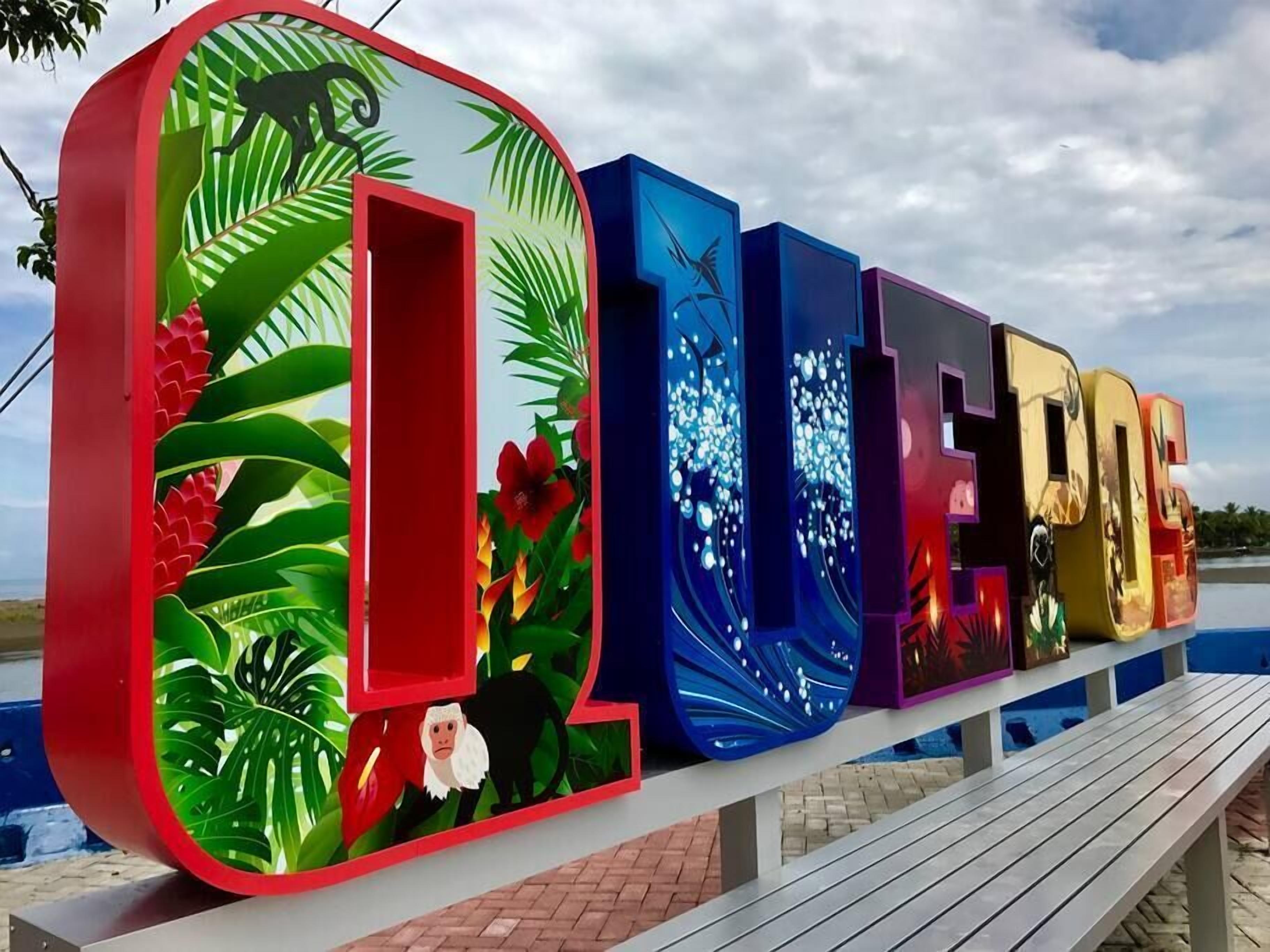 Une enseigne extérieure colorée, avec le mot « OCÉAN » écrit en grandes lettres, entouré d’illustrations de feuilles et de fleurs tropicales.