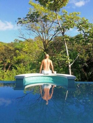 A man sitting on a pool edge with a tree in the background. - Moonshine Inn - 1 BR Studio Loft with Ocean & Jungle Views, Moonshine Inn -- 1BR Studio Loft (Quepos)