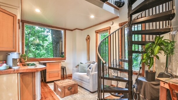 A cozy living area with a wooden staircase, a sofa, and a dining table.