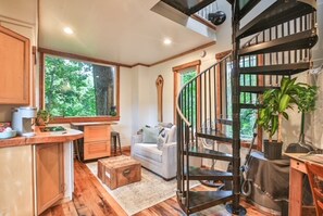 Un salon chaleureux avec un escalier en bois, un canapé et une table à manger.