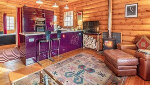 A log cabin interior with a kitchen, dining area, and living room. - Grebe Lodge (Lodge 6) (Frettenham)