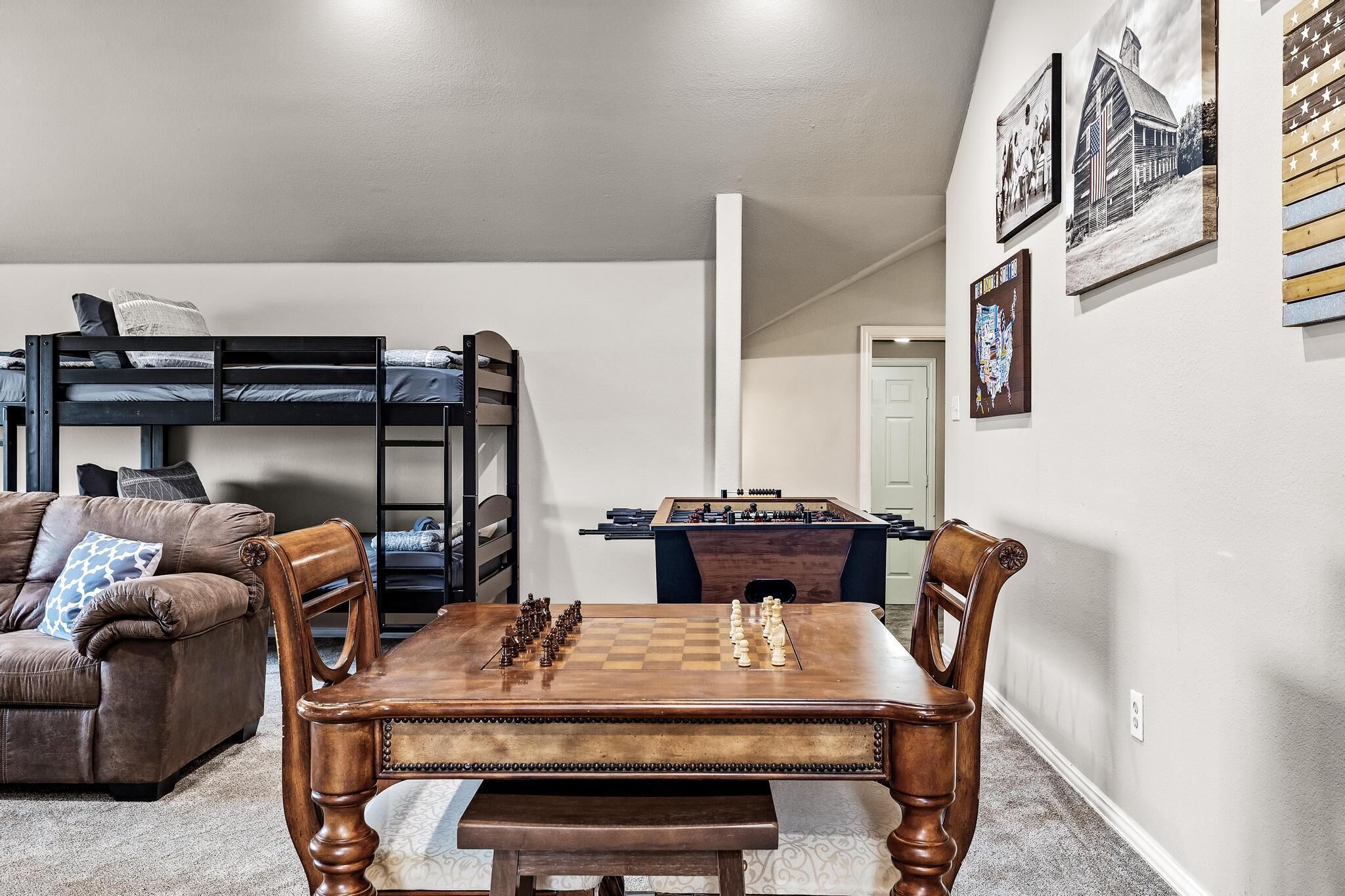 Una sala de estar con una mesa de centro de madera, un sofá, una cama litera y una mesa de futbolín.