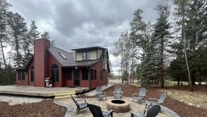 Une maison rouge dotée d’un patio aménagé avec des meubles d’extérieur et un foyer.