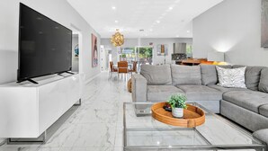 Una sala de estar moderna con un televisor de pantalla plana, un sofá modular y una mesa de centro de vidrio.