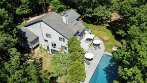 Une grande maison avec une piscine, entourée d’arbres.