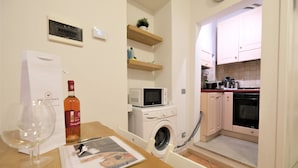 A compact kitchen with a washing machine, microwave, and oven. - Wine Apartments Florence Dolcetto (Florence)