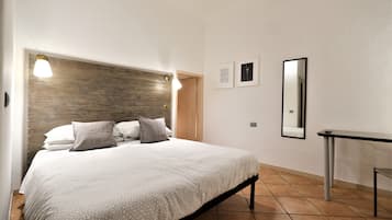 Un dormitorio con cama, lámparas de noche, una mesita de noche, un espejo y dos cuadros en la pared.