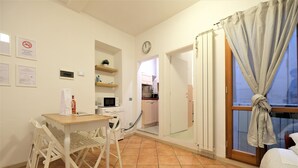 A compact room with a dining table and chairs, a microwave, a small kitchen area, and a window with curtains. - Wine Apartments Florence Dolcetto (Florence)