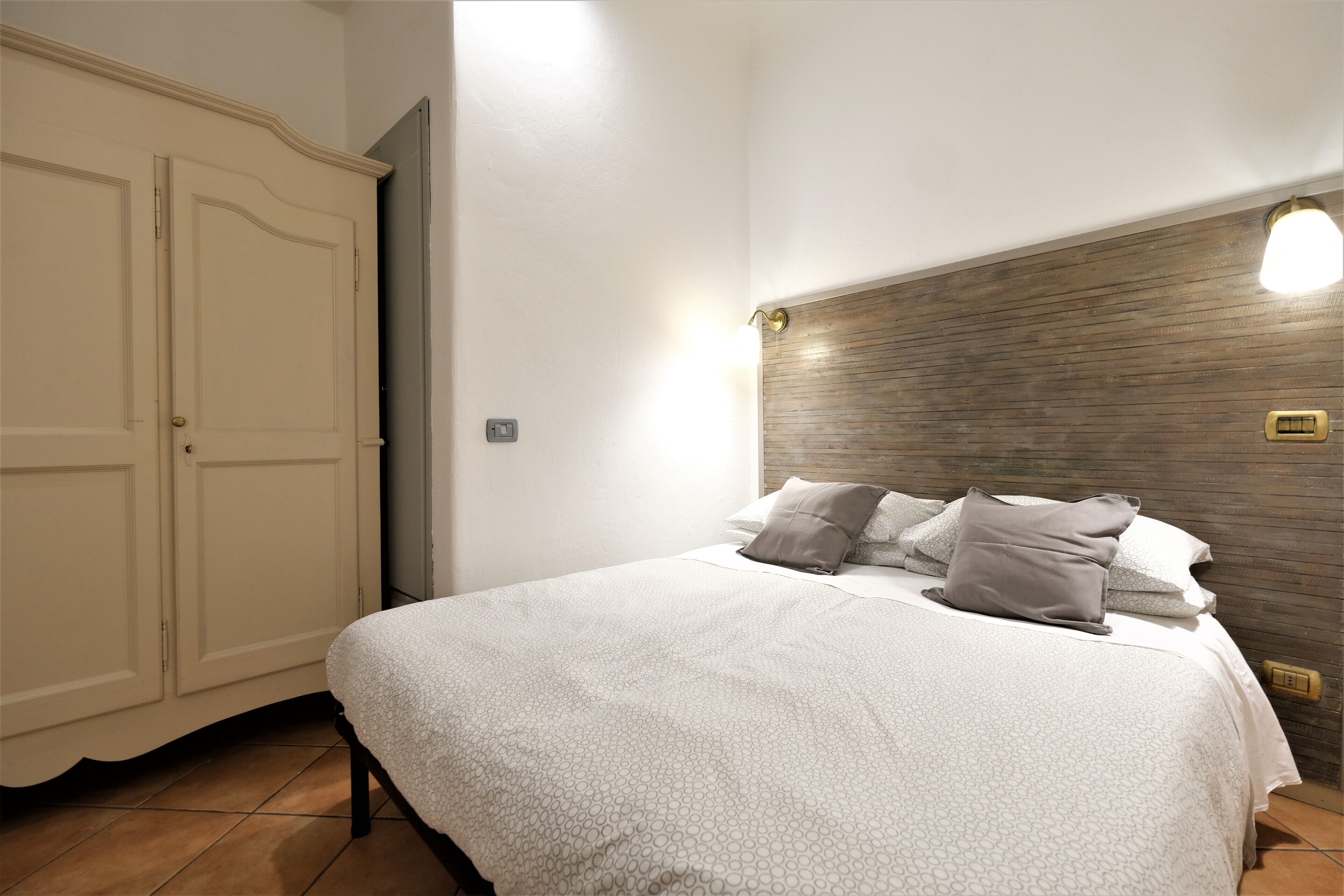 A bedroom with a bed, a wardrobe, and a wall-mounted light fixture.