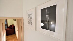 A hallway with framed wine-related artwork and a lit lamp. - Wine Apartments Florence Dolcetto (Florence)