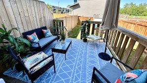 A patio with a blue patterned rug, outdoor furniture, and a wooden fence. - Gorgeous townhome 5 min walk to the stunning lake. (Sylvan Lake)