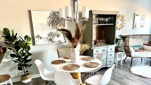A dining area with a round table, white chairs, and a bar area with a 'BAR' sign. - Gorgeous townhome 5 min walk to the stunning lake. (Sylvan Lake)