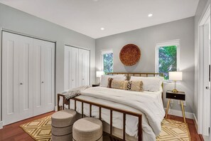 A bedroom with a bed, two nightstands, a round woven wall art, and two windows with greenery outside. - Victoria Park Overlook: Rooftop views (Fort Lauderdale)
