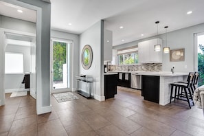 A modern kitchen with a central island, recessed lighting, and a view of greenery outside. - Victoria Park Overlook: Rooftop views (Fort Lauderdale)