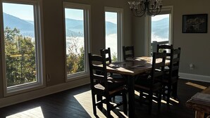 A dining area with a large table and chairs, large windows with mountain views, and a chandelier. - Almost Heaven - Mountain views beyond compare! (Hiawassee)