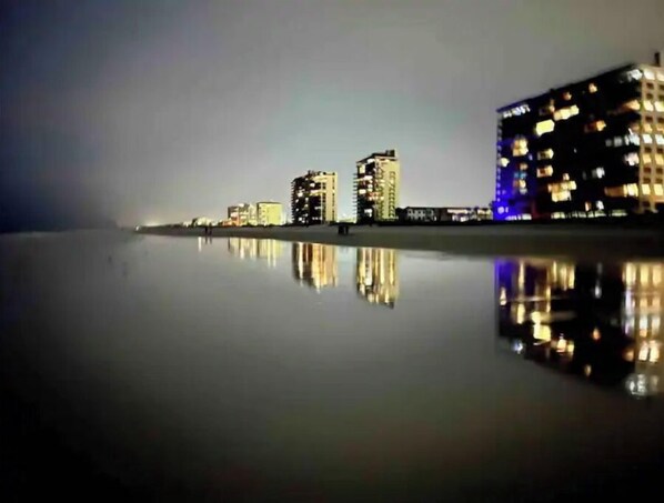 Un paisaje urbano nocturno con edificios reflejados en aguas tranquilas.