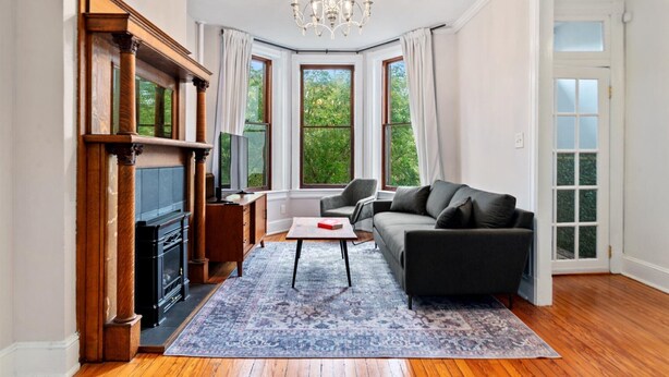 Ein Wohnzimmer mit Kamin, einer Couch, einem Couchtisch und einer Deckenleuchte.