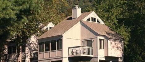 A two-story house with a covered porch, surrounded by trees and a grassy yard.