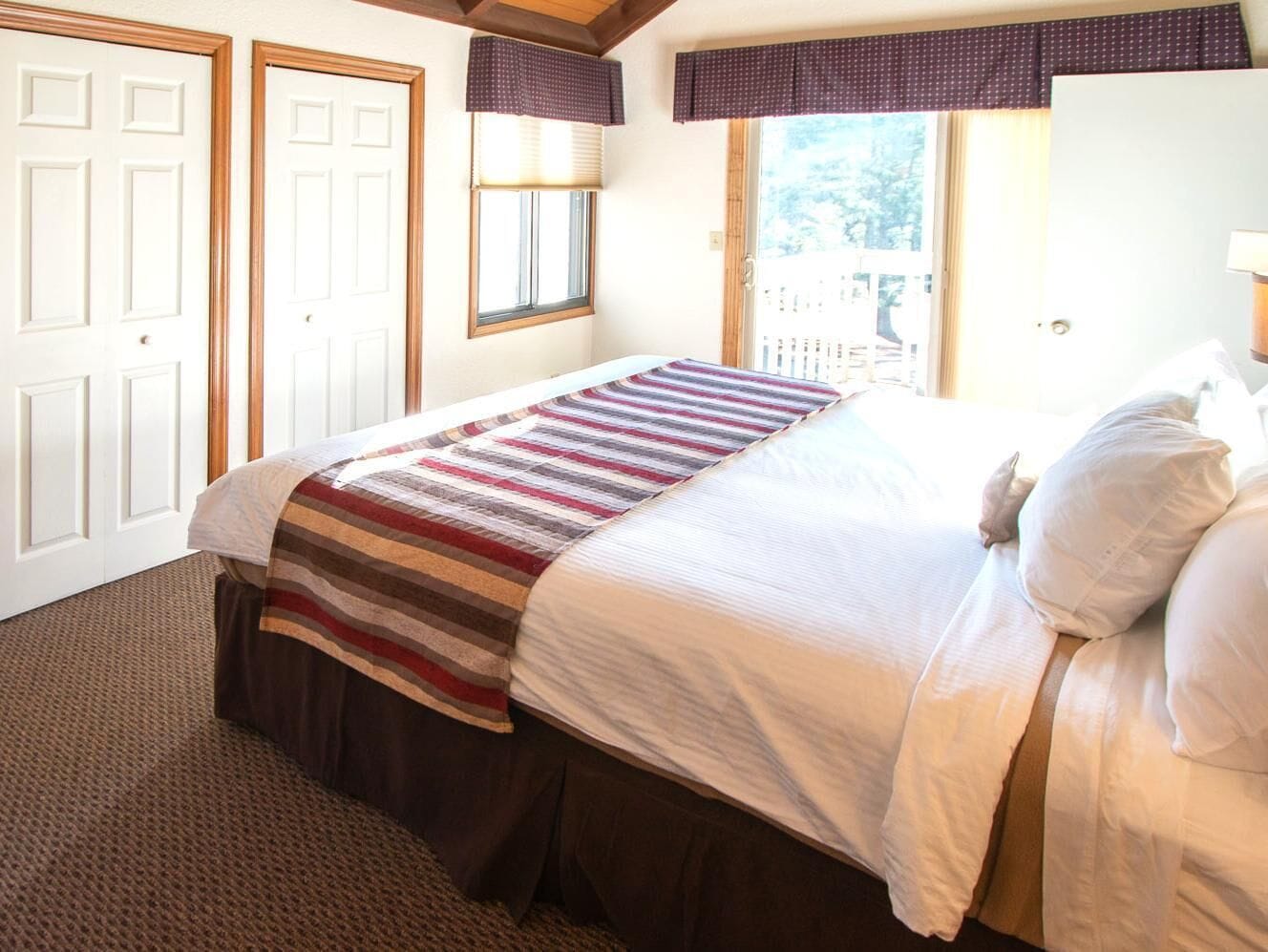 A bedroom with a bed, a window, and a door.