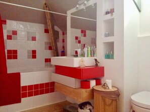Een bad/douchecombinatie, zeep, shampoo, toiletpapier