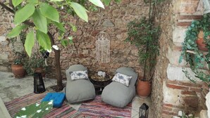 Ein gemütlicher Sitzbereich im Freien mit zwei gepolsterten Sesseln, einem kleinen Tisch mit Dekoration und einem Wandbehang aus Makramee.