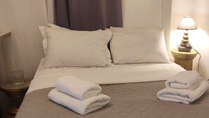 Ein ordentlich bezogenes Bett mit weißen Leinentüchern, zwei Kissen und zwei gefalteten Handtüchern.
