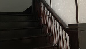A wooden staircase with a handrail and balusters, leading to an upper floor.