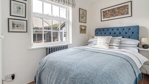 Une chambre avec un grand lit, une fenêtre donnant sur un beau paysage et plusieurs tableaux encadrés accrochés au mur.