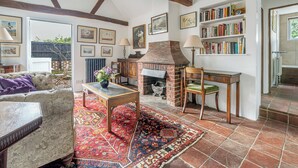 Un salon chaleureux avec une cheminée, une bibliothèque et un tapis à motifs.