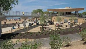 Een buitengebied met een overdekte zithoek, picknicktafels en een voetgangersbrug.