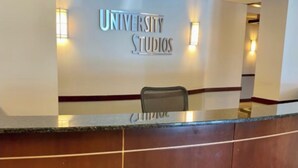 Een receptiebalie met een bord waarop 'UNIVERSITY STUDIOS' staat en een naamplaatje met de naam 'JIMMY'.