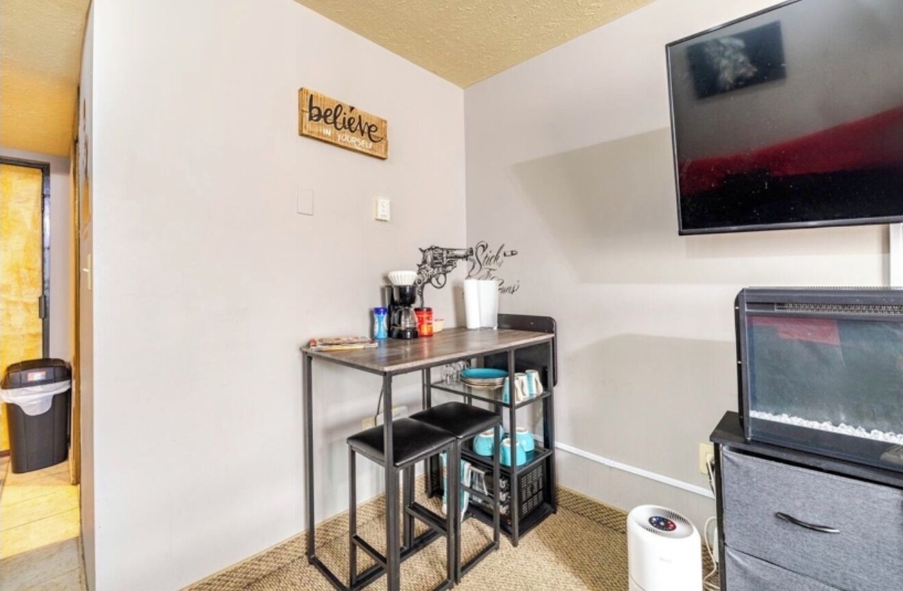 A compact living space with a kitchenette, a mounted TV, and a motivational wall sign.