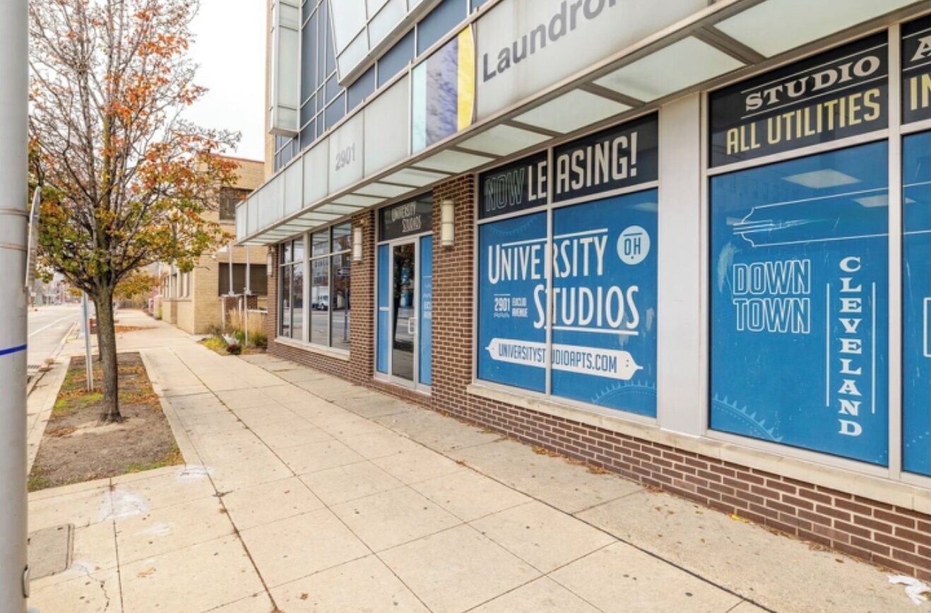 A building with large blue windows advertising 'University Studios' and 'Downtown Cleveland'.
