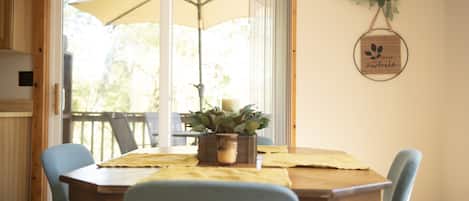 A dining area with a wooden table, blue chairs, a potted plant, and a wall-mounted sign.