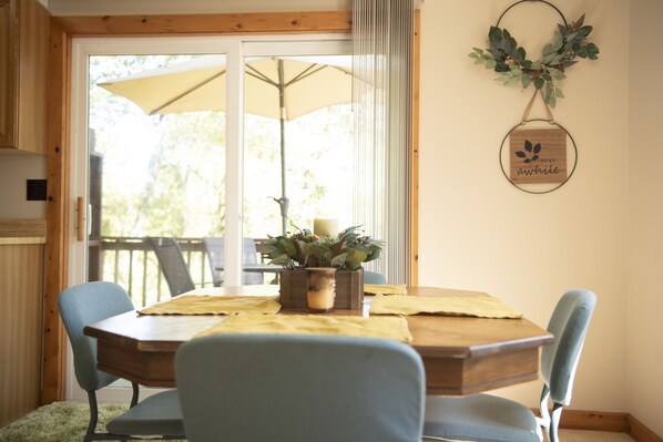 A dining area with a wooden table, blue chairs, a potted plant, and a wall-mounted sign.