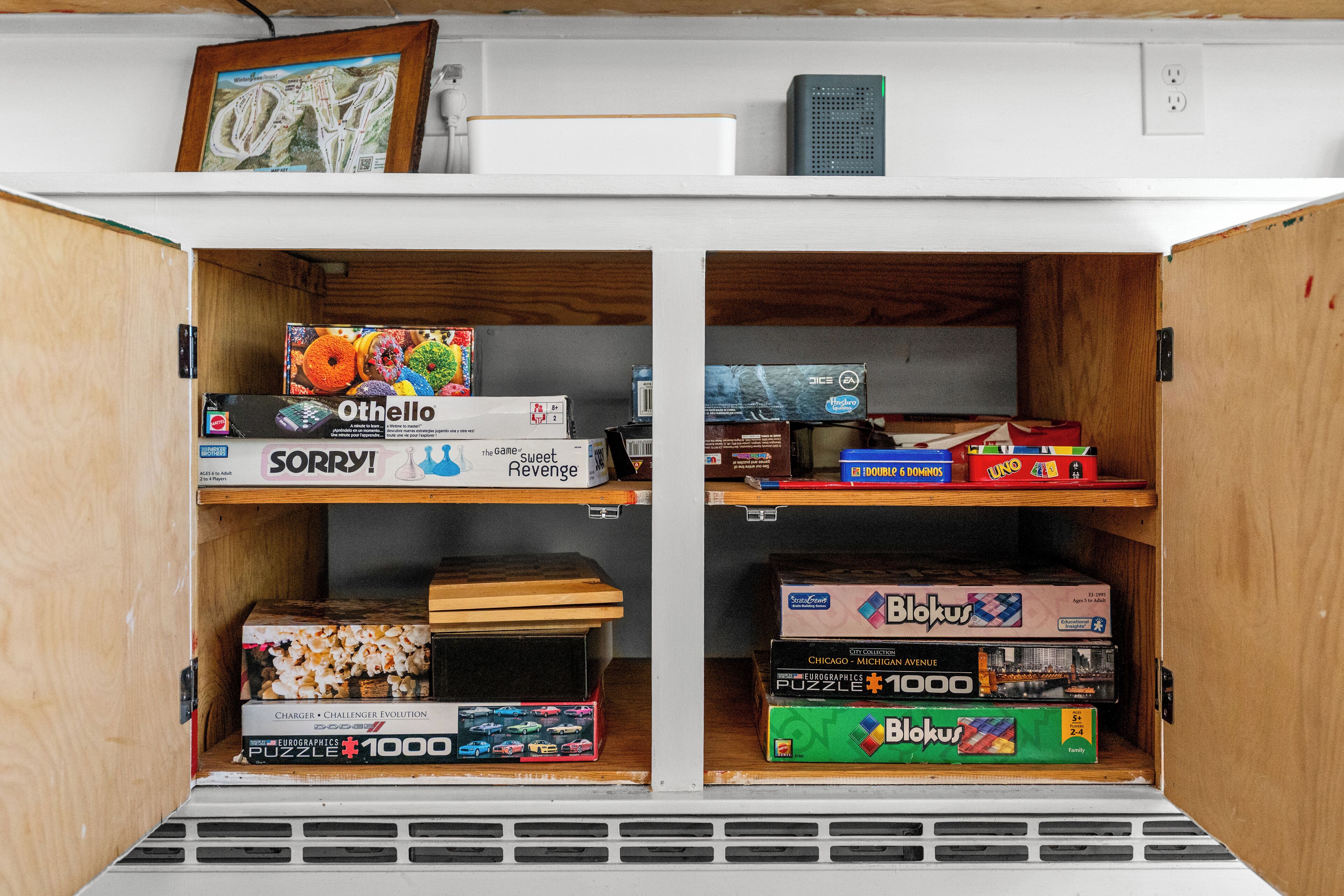 A storage unit with shelves containing board games and puzzles.
